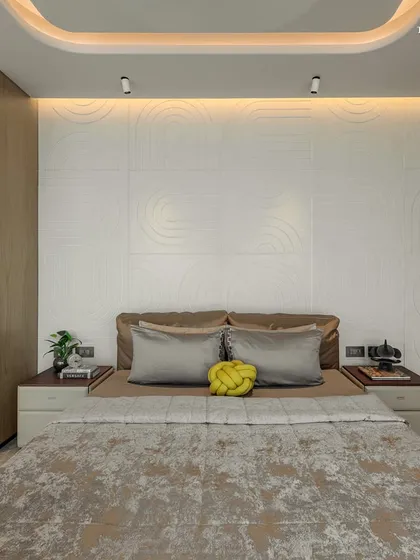 A minimalist bedroom design in the Shivaji Park residence, where a textured white wall serves as a serene headboard. The layout prioritizes function and flow, creating a spectacle of refined balance between material, memory, and modern design.