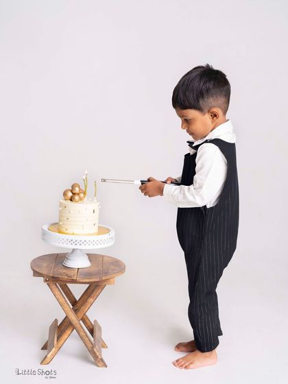 A little gentleman getting ready to celebrate his birthday. This candid shot of him lighting his own cake is a unique and charming moment.