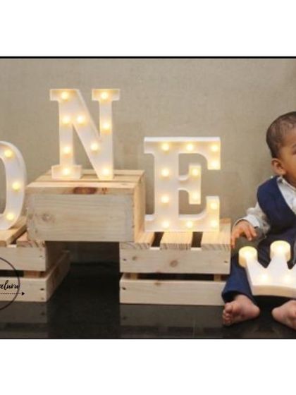 Here's the little prince Aryan enjoying his party. We used stacked wooden crates to display the 'ONE' marquee letters and added a light-up crown prop for him to hold, making his first birthday photos extra special.