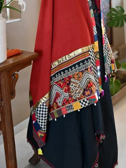 A detail shot of the Kutch and Laos wrap, draped to show the rich rust color of the Kala cotton and the intricate, 30-year-old 'Tin Sinh' textile fragment from Luang Prabang.