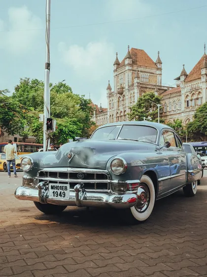 A stunning vintage Cadillac from 1949, its classic lines and chrome details shining against the backdrop of Mumbai's heritage architecture.