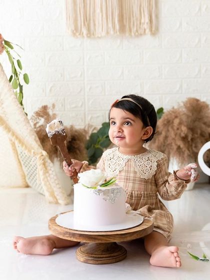 A wider shot of the boho cake smash, showing the complete setup with the 'One' sign and floral arrangements.