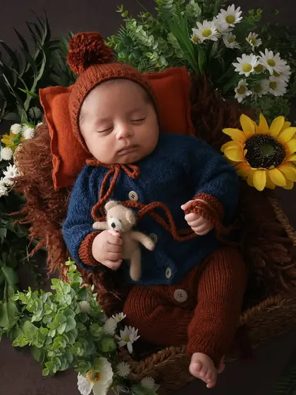 A perfect little bundle. This overhead shot showcases the complete setup, with the baby nestled in a basket surrounded by sunflowers and greenery. The textures and colors come together to create a beautiful composition.