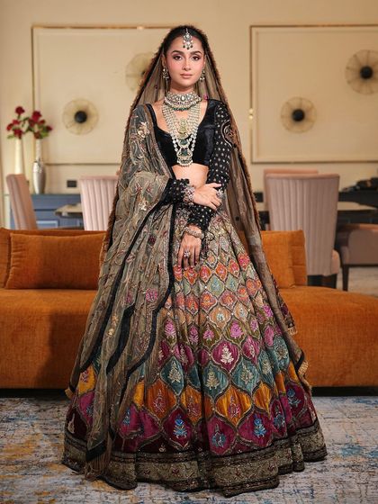 A full view of this bride's magnificent multi-colored lehenga. The makeup is kept minimal and elegant to balance the vibrant outfit, focusing on a flawless base and softly defined eyes.