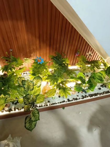 This under-stair garden features a mix of white and black pebbles, along with some colorful artificial flowers for an extra decorative touch.