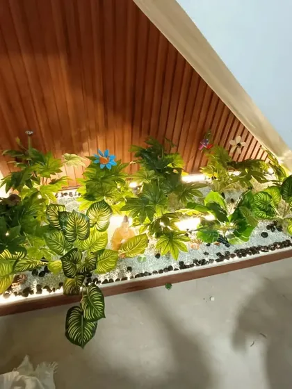 This under-stair garden features a mix of white and black pebbles, along with some colorful artificial flowers for an extra decorative touch.