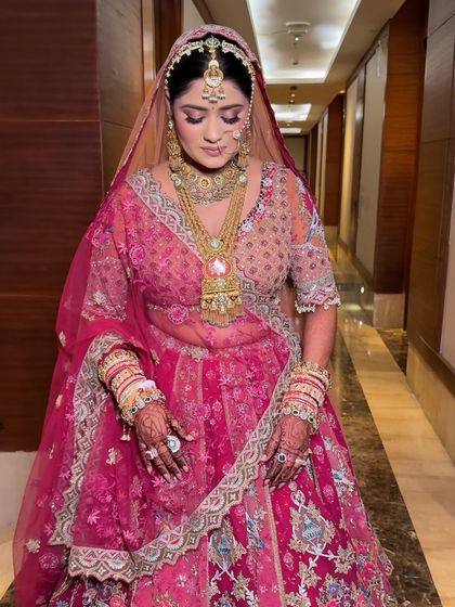 A beautiful portrait of the bride looking down, showcasing the elegant draping of her dupatta and the flawless finish of her makeup.