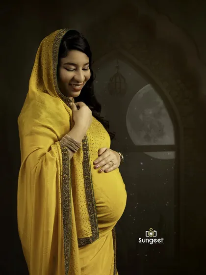 A smiling portrait of the mother-to-be in a yellow saree, with a creative edit of a moonlit window in the background, adding a touch of magic.