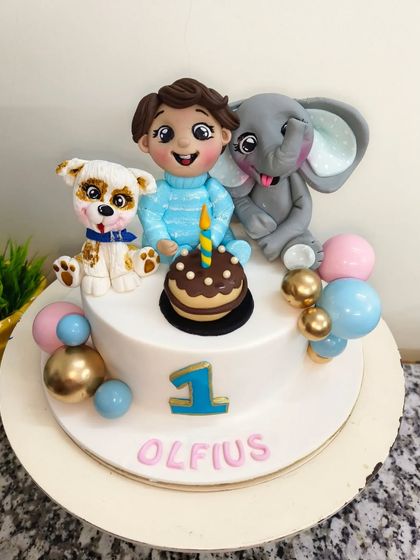 A first birthday celebration with some furry and friendly pals. This simple and sweet cake is topped with a custom figurine of the birthday boy, along with his favorite elephant and puppy toys, all made from edible fondant.