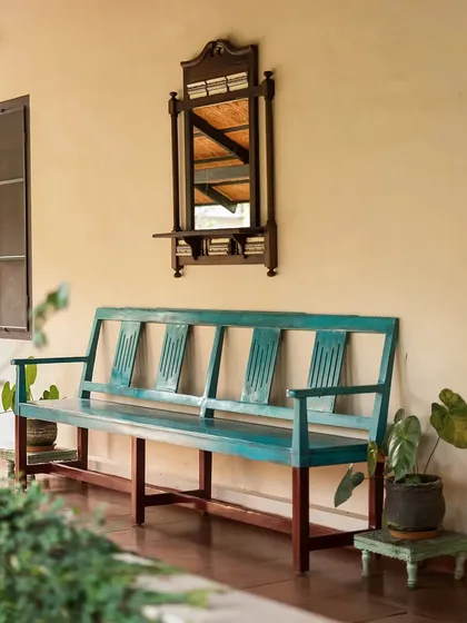 A rustic turquoise bench and a vintage-style mirror on a veranda. This charming detail adds a pop of color and a touch of old-world charm to the resort's exterior.