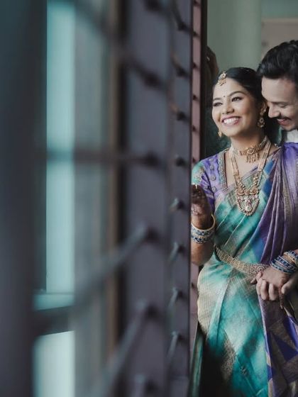 A happy, candid moment between the couple, framed by a window during their Varapooje.