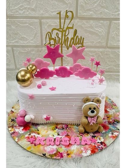 Celebrating a special milestone with a half-birthday cake. This adorable design features a teddy bear, pink stars, and a "1/2 Birthday" topper.