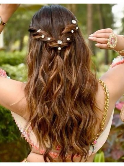 A simple and romantic half-up hairstyle. The twisted braids are accented with small pearls, and the hair is styled in soft, natural waves.
