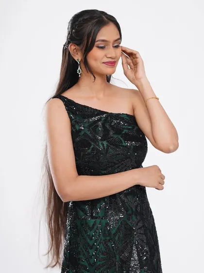 A chic and modern black one-shoulder sequin gown. The simple silhouette is elevated by the sparkling fabric, making it a great choice for a cocktail party.