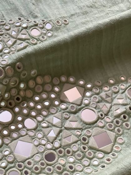 A macro shot of the Kutchi mirrorwork, detailing the thread that holds each mirror in place.