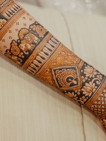 A detailed shot of the forearm, showcasing a band of elephants and other traditional motifs. The contrast between the dark and light areas is beautiful.