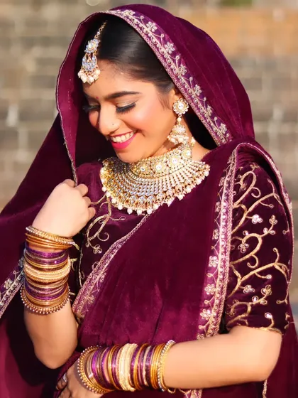 A shy and happy smile from the bride, her face partially covered by her dupatta.