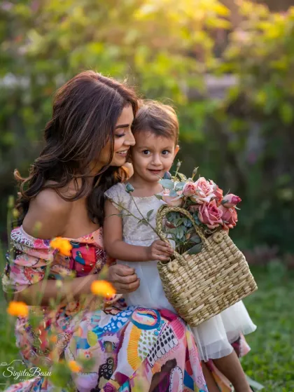 A beautiful, sun-drenched moment between actress Shriya Saran and her daughter Radha. The flowers, the soft light, and their loving interaction create a portrait that feels joyful and idyllic, a perfect memory of a mother's love in a garden.