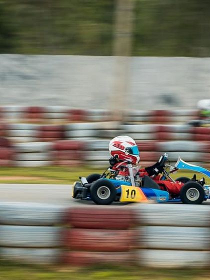 A Micro driver in the number 10 kart at speed, framed by the track's tyre barriers.
