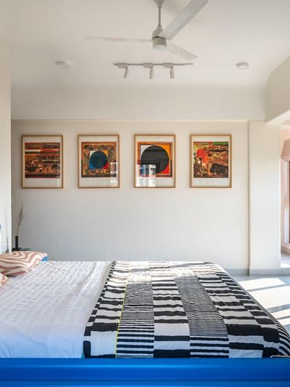 This wide view of the bedroom shows how we balanced bold furniture with a minimalist backdrop. The vibrant blue bed and sculptural pink leather drawers are set against clean white walls and framed by modern art, creating a space that is both playful and chic.