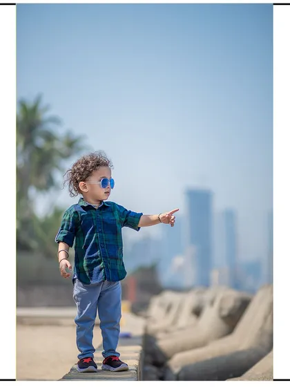 A stylish shot of a toddler enjoying the view at a Mumbai seaside location. The city skyline in the background provides a unique urban context for this child's portrait.