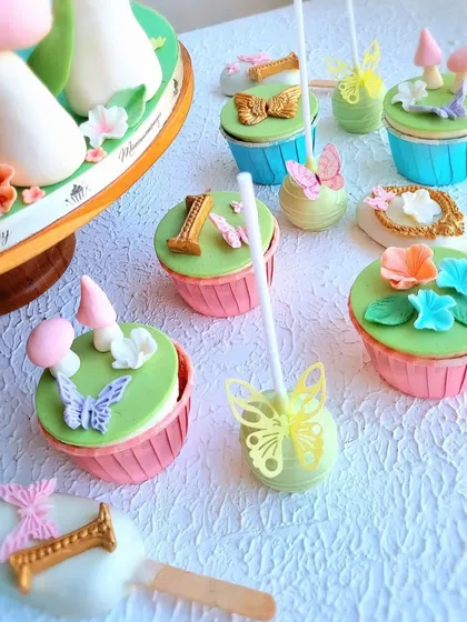 A close-up of the detailed cupcakes and cakesicles from the enchanted garden dessert table.