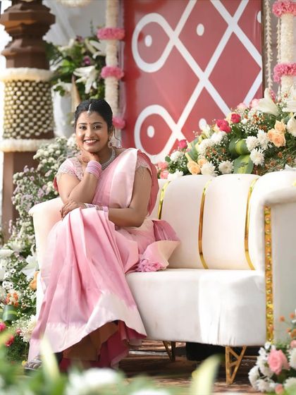 The complete look for Dr. Namratha's engagement. The light pink Kanchipuram saree is draped elegantly, and her hair is styled in a neat braid, suitable for the outdoor setting.