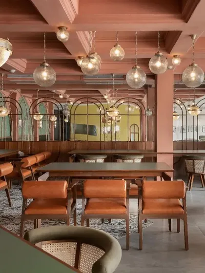 The interior of Karim's restaurant in Bhubaneswar, a contemporary reimagining of Old Delhi's aesthetic. The design uses a rich palette of terracotta, green, and brass.