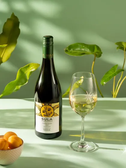 A bottle of Sula white wine with a filled glass, styled with fresh greenery. This is a clean, commercial product shot perfect for advertising.