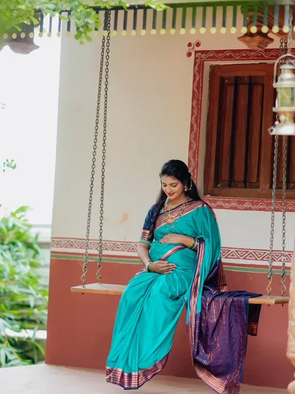 A tranquil solo shot of the expectant mother on a swing, framed by the leaves of a tree.