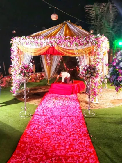 A lush mandap setup on an artificial grass lawn, with a flower-petal-covered aisle leading to the floral-draped structure.