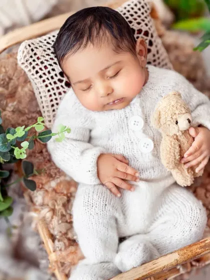 A top-down view of this sweet baby boy in his knitted outfit, cuddling a teddy bear. This angle is wonderful for capturing the symmetry and peace of a sleeping newborn.