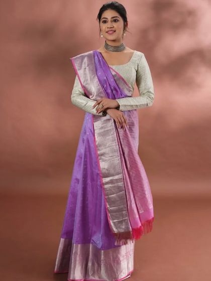A model wearing a beautiful purple saree with a silver zari border. This piece showcases how our traditional weaves can be styled for a contemporary and elegant look.
