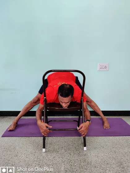 A variation of Prasarita Padottanasana (Wide-Legged Forward Bend) using a chair to deepen the stretch and release the spine.