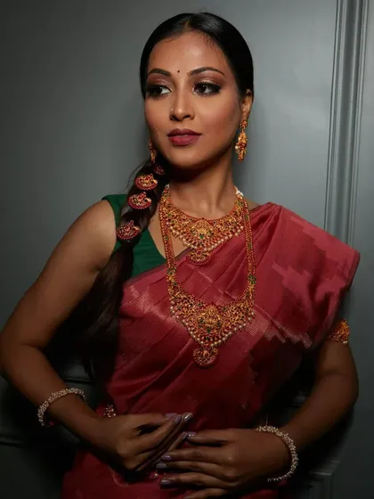 A full view of a classic South Indian bridal look. The makeup, hair, and styling all come together to honor the rich traditions, from the temple jewelry to the elegant braided hairstyle.