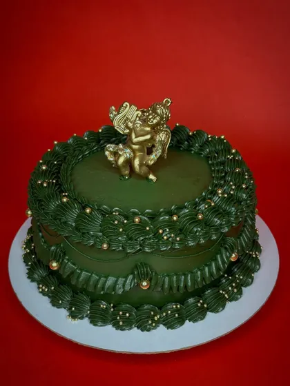 Is it Christmas yet? This vintage-style Christmas cake is a deep forest green with intricate piping and a golden cherub topper. It brings a touch of old-world elegance to the holidays.