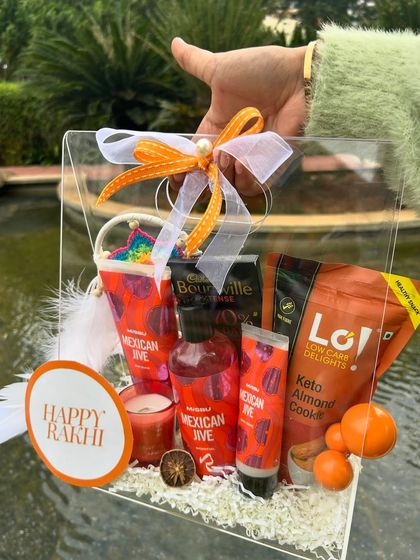 A vibrant orange-themed Rakhi hamper. The "Mexican Jive" scented products and keto-friendly cookies make it a unique and zesty gift.