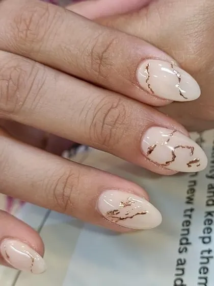 A chic and minimalist design featuring a nude base with delicate rose gold foil lines, creating a kintsugi or broken-marble effect. This is all done by hand for a unique finish.