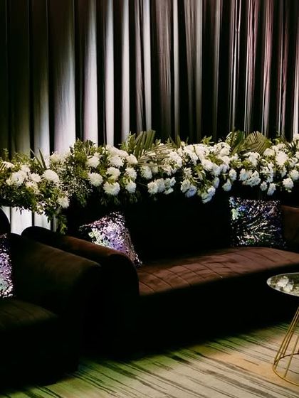 A luxurious lounge area for a Goa Sangeet, with a long sofa draped in a cascade of white flowers and accented with shimmering sequin pillows.