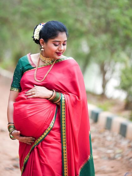 A beautiful outdoor portrait of a mom-to-be in a traditional red saree.