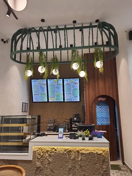 A custom-made light fixture over the cafe counter, adorned with hanging artificial plants and globe lights for a stylish green accent.
