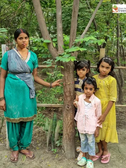 A family stands with a tree they have adopted as part of our Rakshabandhan initiative. This simple act fosters a deep, emotional connection to nature.