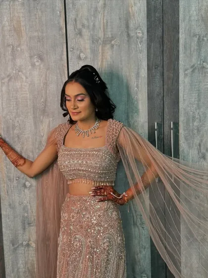 The flowy cape sleeves of her sangeet outfit are perfectly complemented by the sleek high ponytail and glamorous makeup.