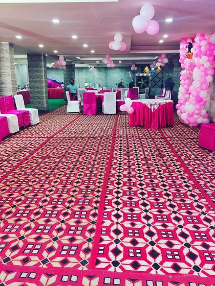 This is the seating arrangement for a pink-themed birthday party. The chairs are covered in pink and white, matching the overall Minnie Mouse balloon decoration.