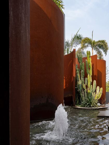 A fountain bubbles next to a Corten steel wall and a tall cactus at KEUS. This detail shot highlights the rich textures and materials used to create this unique desert-modern water feature.