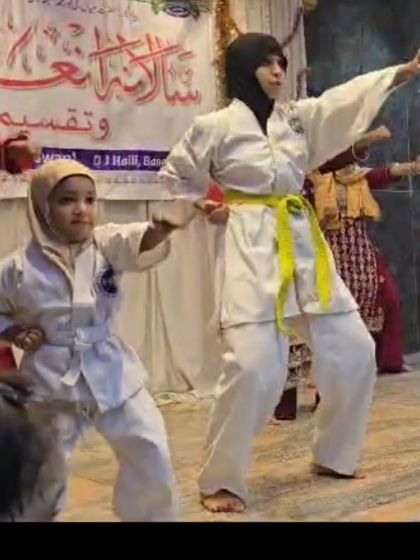 Passing on the knowledge. An older student and a young girl demonstrate a Taekwondo form together, showing the mentorship within our XMF family.