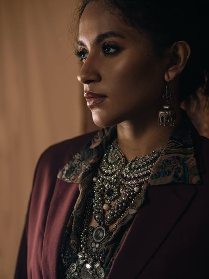A profile view from the same regal series, this time focusing on the silhouette and the layers of jewelry. The soft side lighting catches the details of the necklace and earring, creating a sense of depth and luxury.