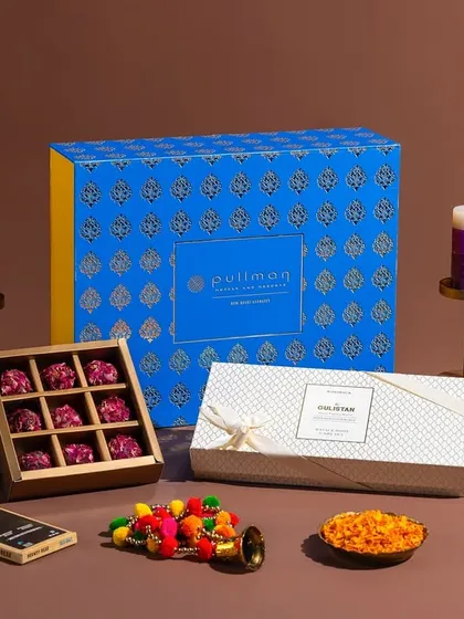 A curated Diwali hamper from Pullman New Delhi Aerocity, featuring chocolates, snacks, and decorative items. The styling creates a warm and inviting festive atmosphere.