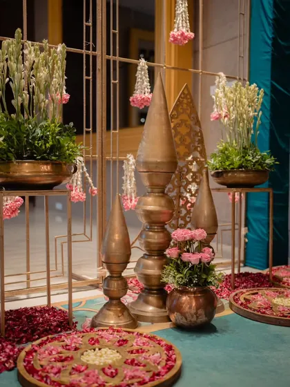 Another shot of the decor corner with brass spires and floral rangolis, highlighting the traditional aesthetic.