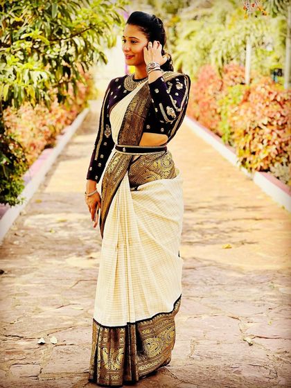 A full view of our client wearing a custom long-sleeve blouse with her traditional Kanjeevaram saree, complete with an embroidered belt.